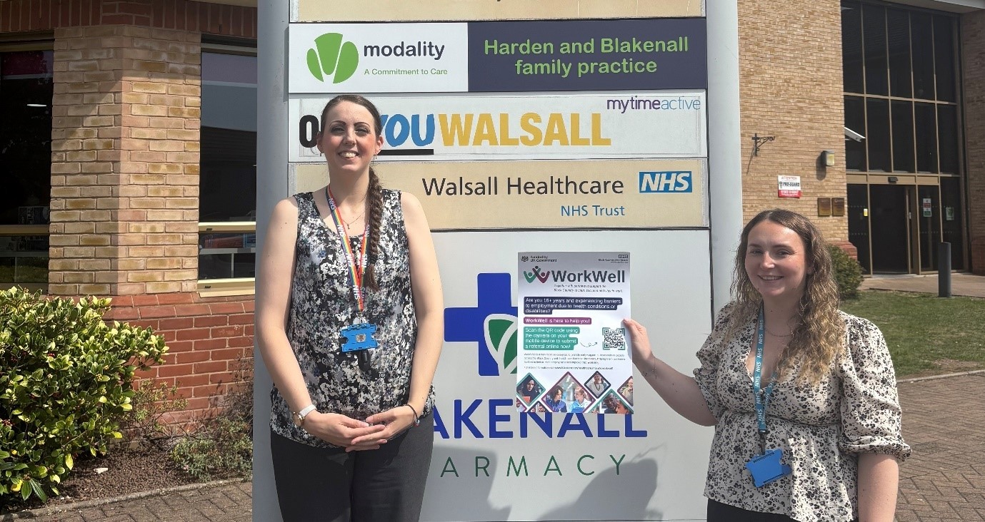 Charlene and Ellen who are social prescribers in front of Harden and Blakenall Family Practice sign holding WorkWell poster